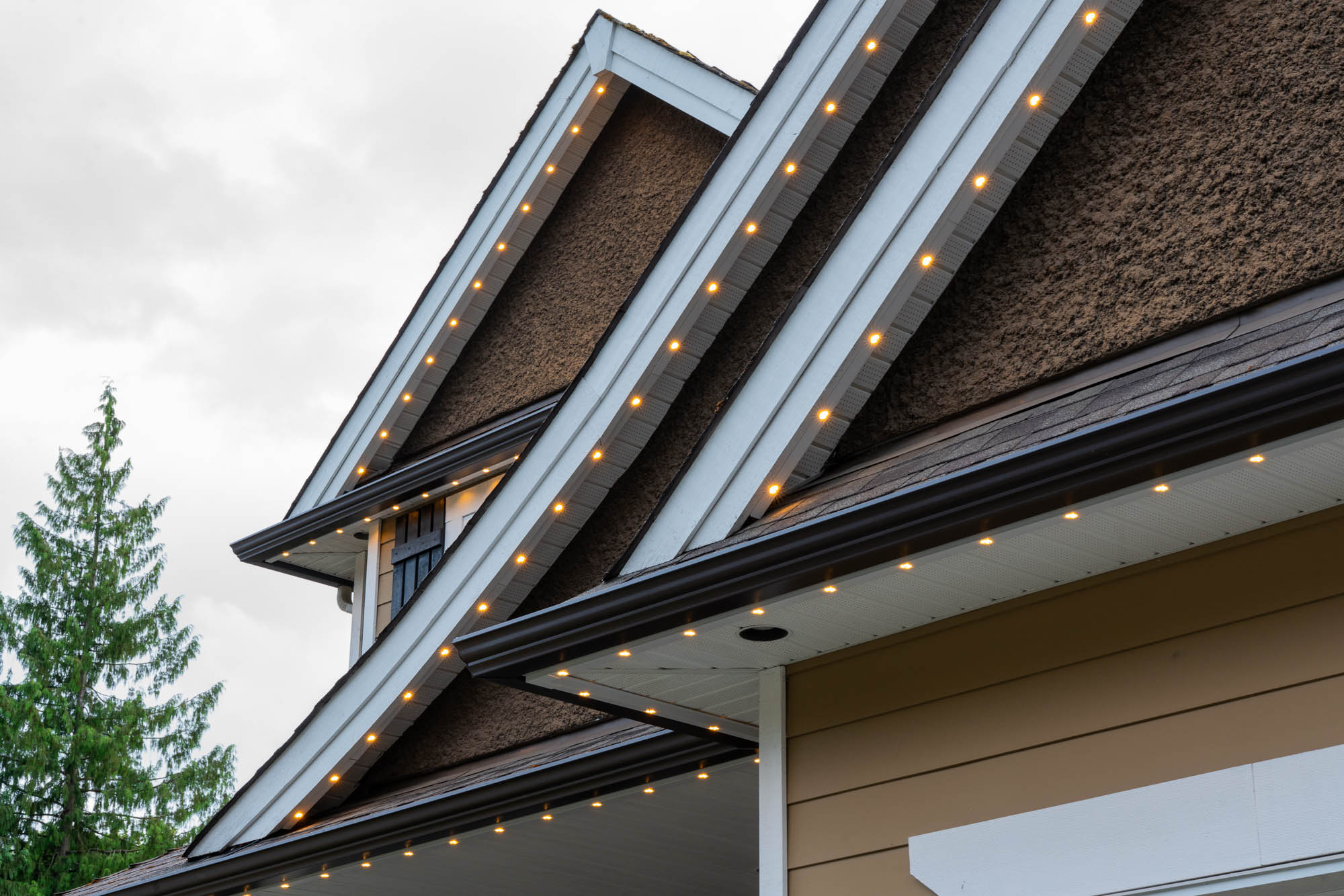 Multi-gable roofline with warm white LEDs glowing at dusk